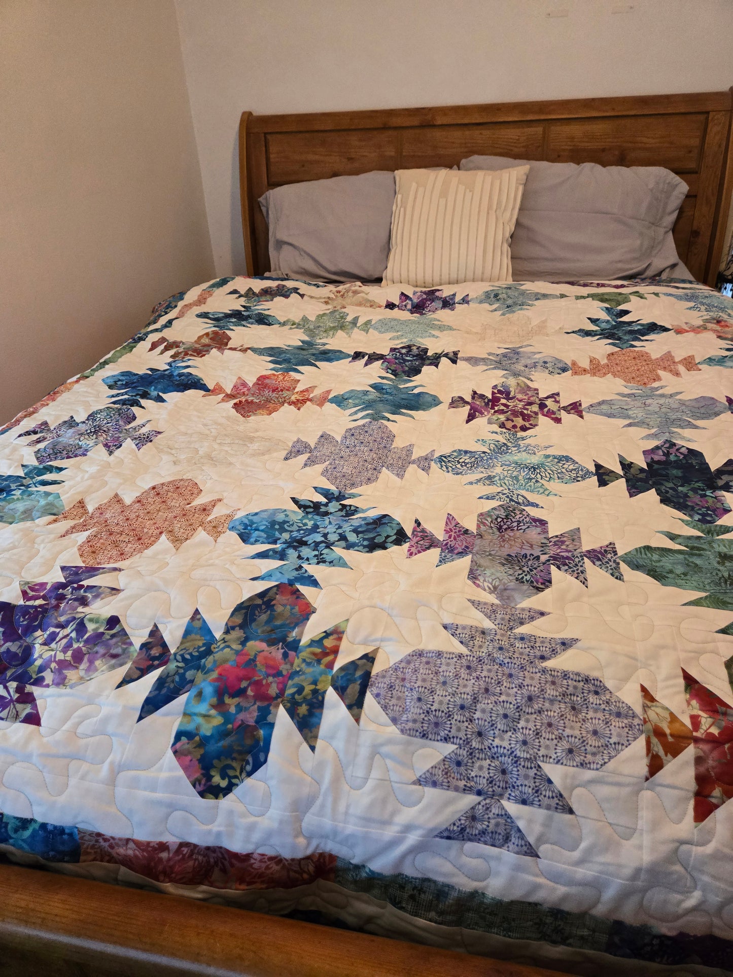 Colorful quilt with geometric pattern draped over a bed in a room.