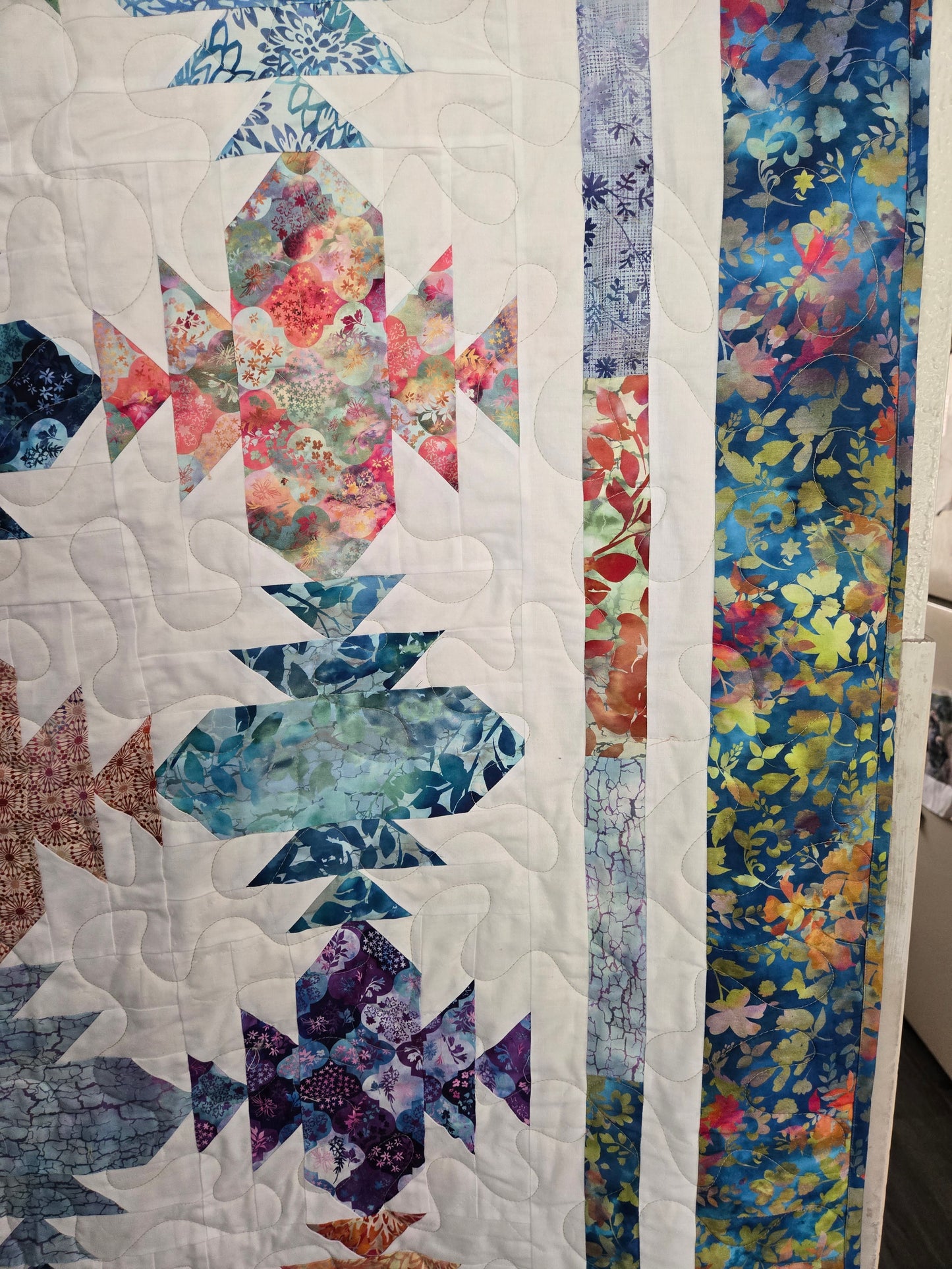 Quilt with geometric and floral patterns on a white background