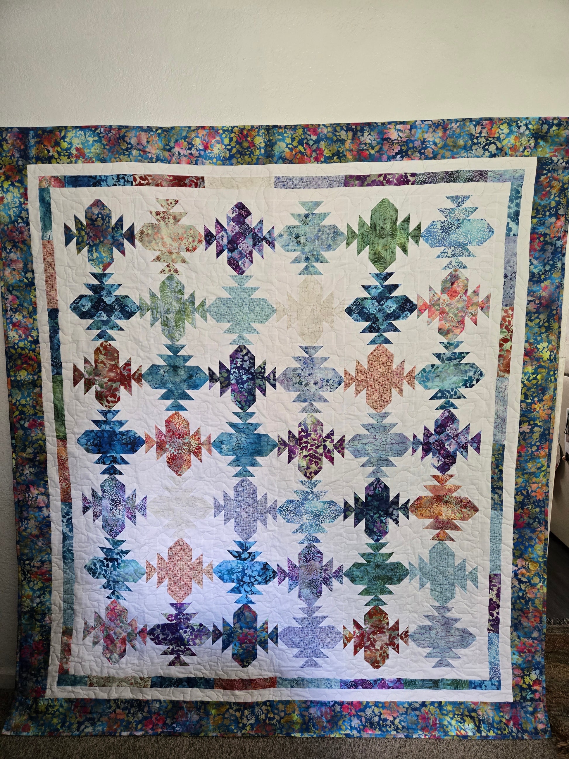 Colorful quilt with geometric patterns on a plain background