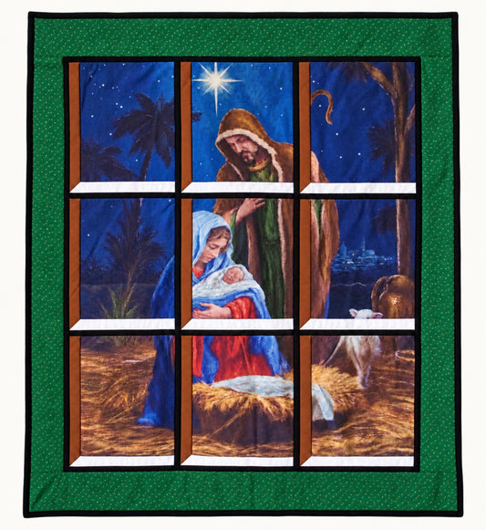 Quilted window-style wall hanging depicting nativity scene showing Mary cradling baby Jesus beside the manger with Joseph and lamb gazing down on Jesus, beneath the Star of Bethlehem, framed by a green border with tiny gold dots.