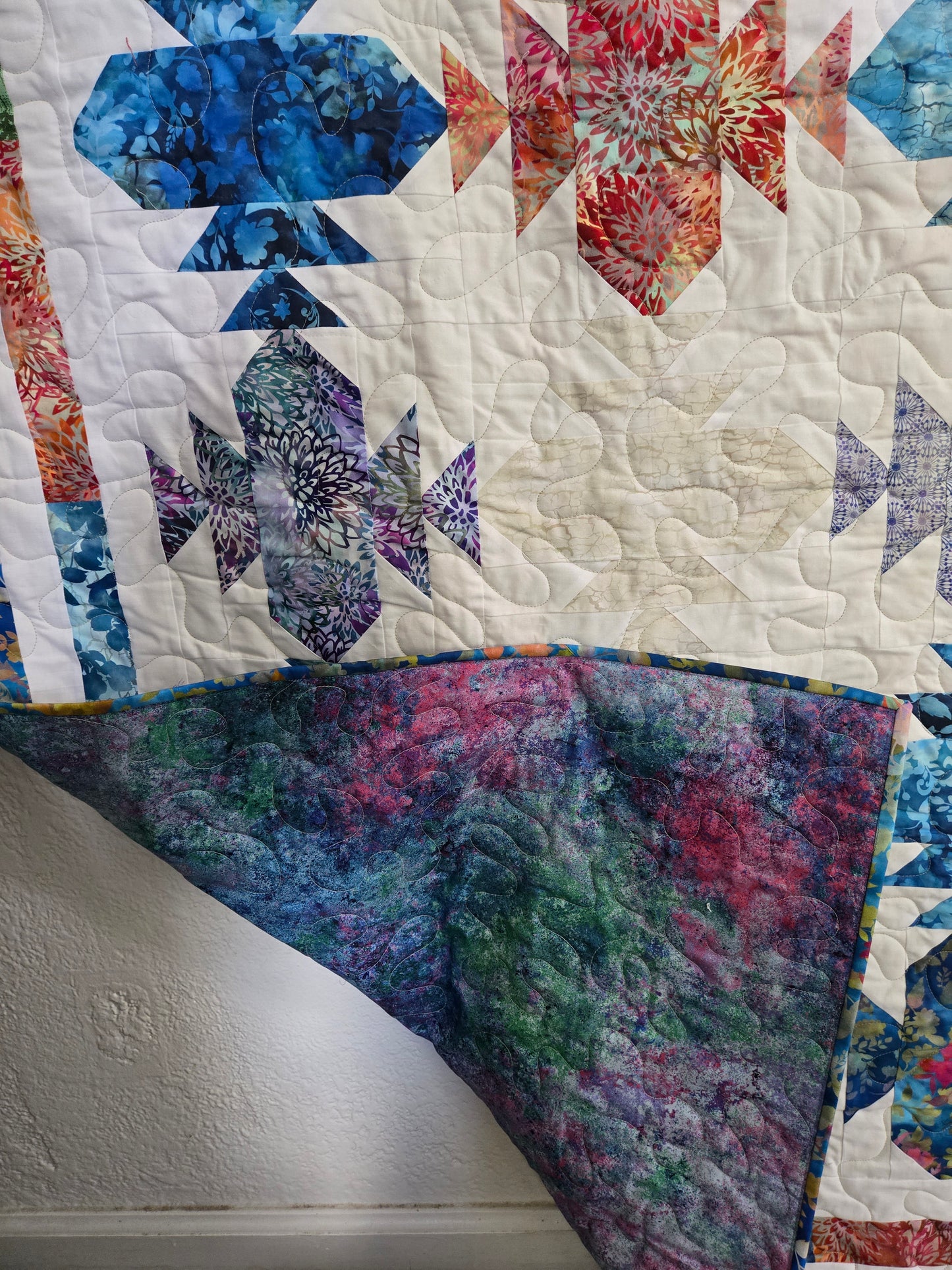 Colorful quilt showing front patteren and vibrant backing