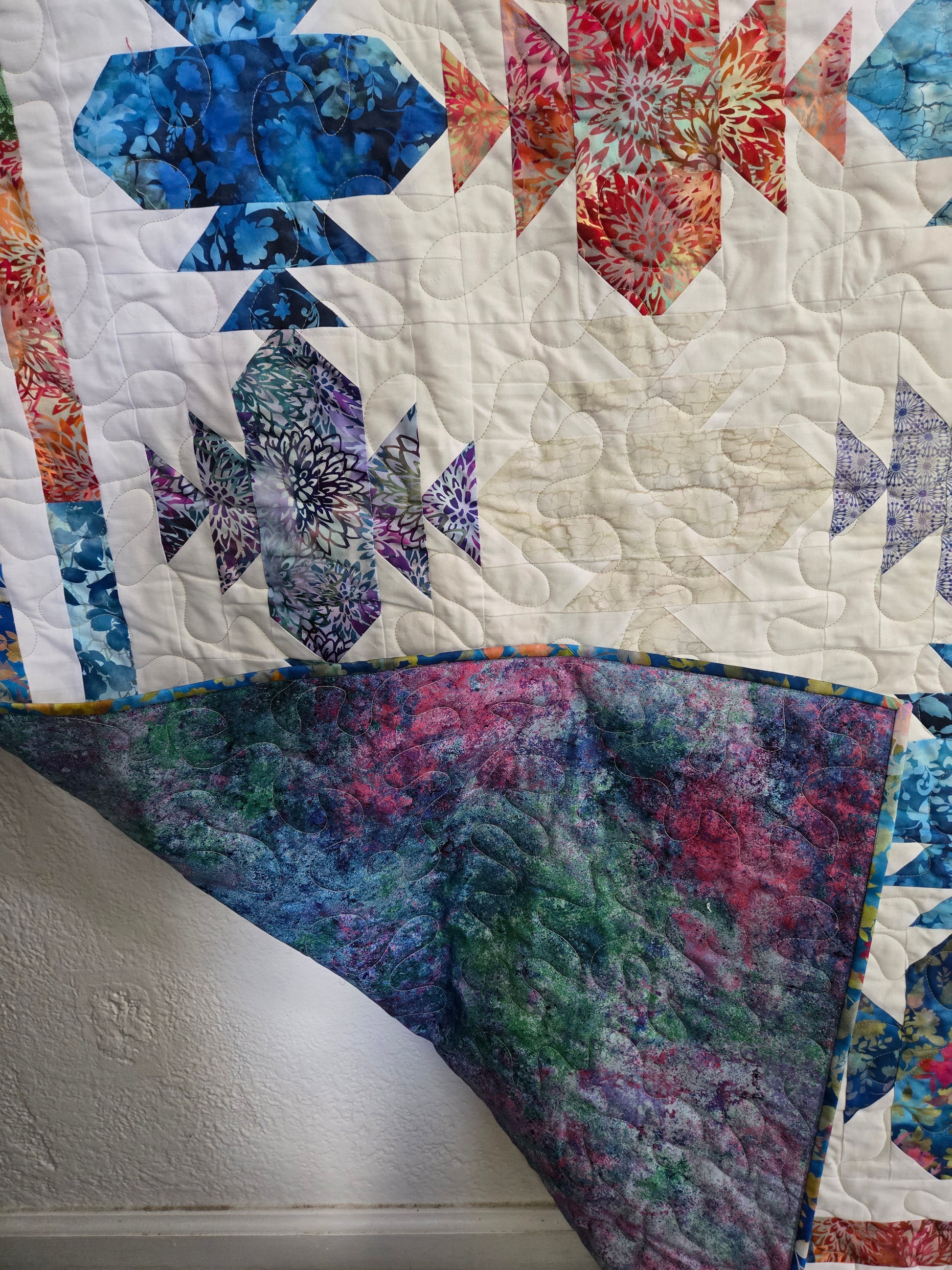 Colorful quilt showing front patteren and vibrant backing